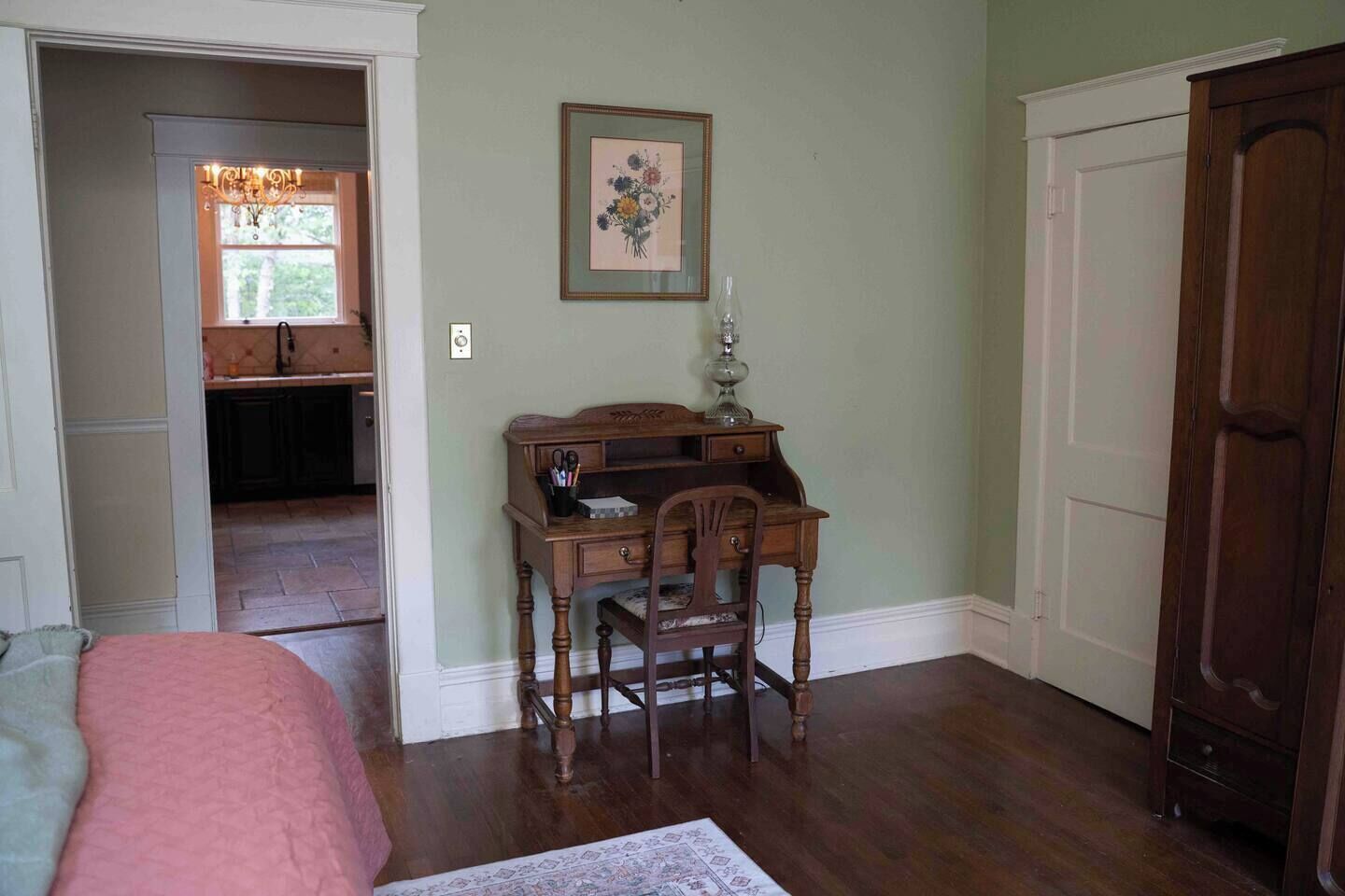 A room with a desk, chair, and a framed floral artwork on the wall.