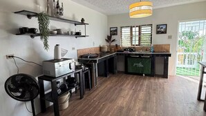 A modern kitchen with wooden flooring, built-in shelves, and a central island. -  4- bedroom/ 12 bed-Oracabessa Seaside Jamaican Manor  Private Beachfront Access (Oracabessa)
