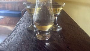 A wooden table with three glasses of a clear liquid, possibly water, in a room with a yellow wall and a plant. -  4- bedroom/ 12 bed-Oracabessa Seaside Jamaican Manor  Private Beachfront Access (Oracabessa)