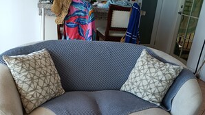 Ein Wohnzimmer mit einer Couch, zwei gemusterten Kissen, einer Fernbedienung und einem Holztablett.