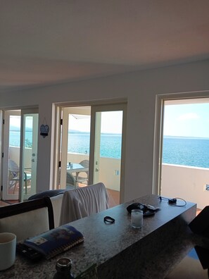 Ein Zimmer mit Meerblick, ein Tisch mit einem Buch und einem Glas sowie ein Stuhl.