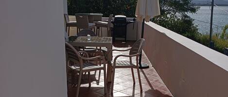 A balcony with outdoor furniture, a grill, and a hose.