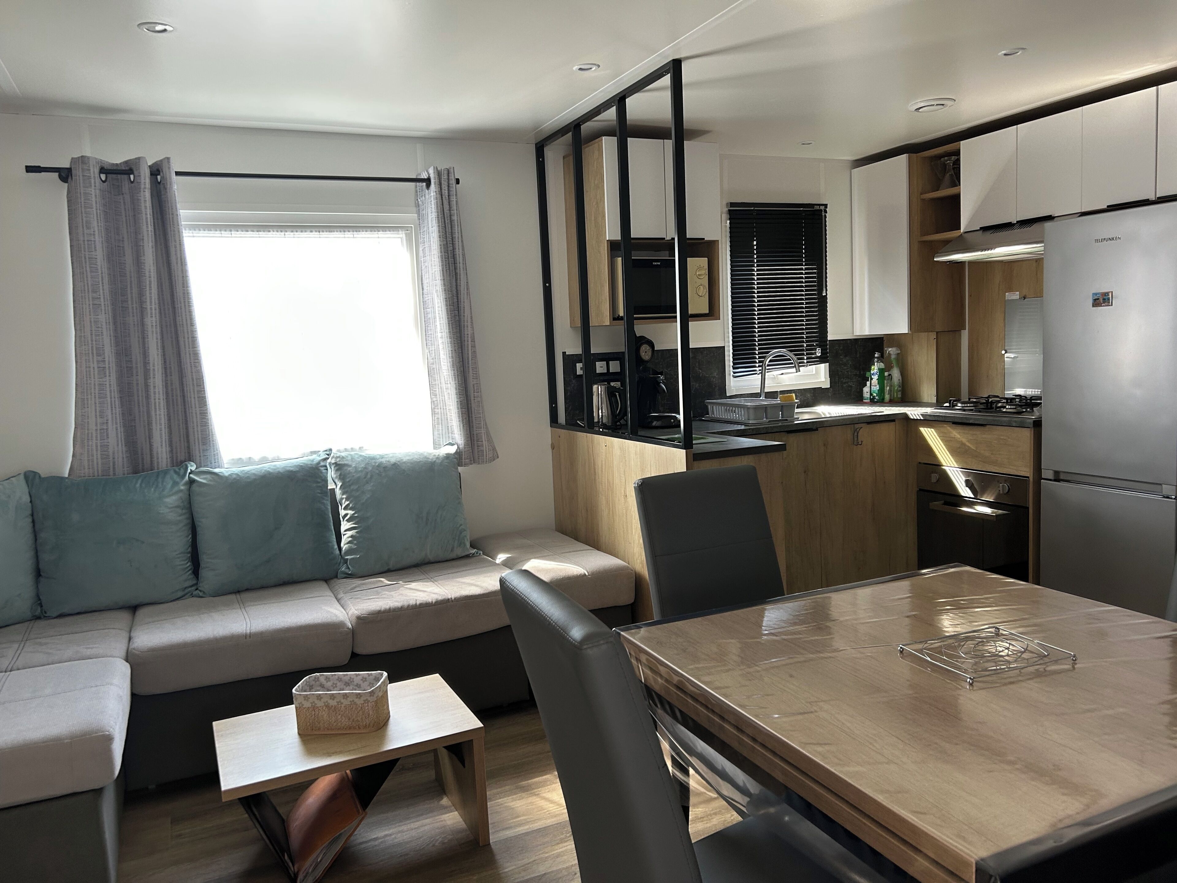 Een knus woongedeelte met een bank, een kleine tafel, een eettafel en een kitchenette.