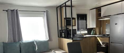 Een knus woongedeelte met een bank, een kleine tafel, een eettafel en een kitchenette.