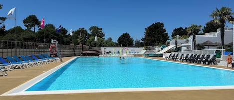 A swimming pool with blue water, surrounded by lounge chairs and a lifeguard stand.