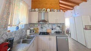 Une cuisine avec des poutres en bois au plafond, un îlot central et un réfrigérateur.