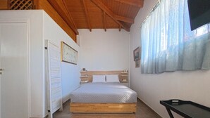 Une chambre à coucher avec un lit, un plafond en bois, une fenêtre avec des rideaux, une table de chevet et un téléviseur fixé au mur.