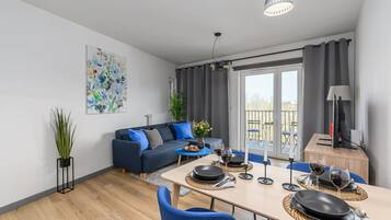 Una sala de estar moderna con sofá, mesa de comedor y un balcón con cortinas.