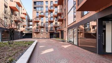 Un moderno edificio de apartamentos con varios balcones, fachada de ladrillo y un patio empedrado.