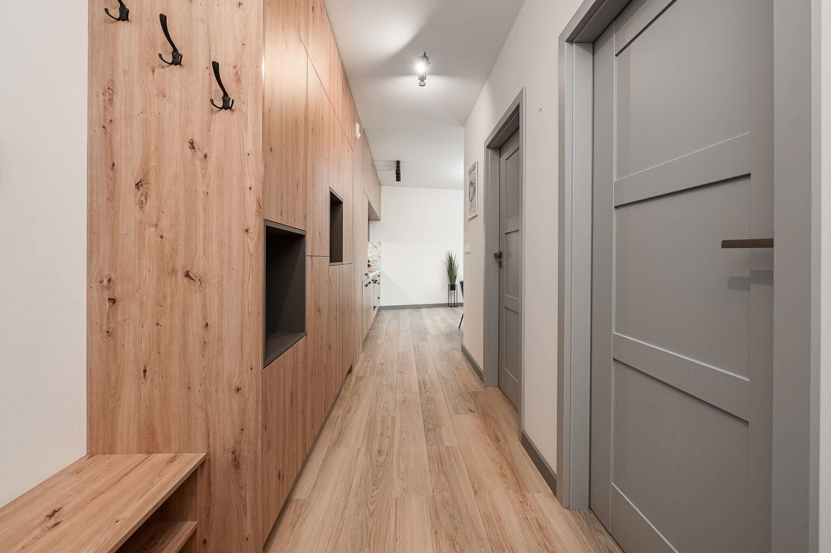 A hallway with wooden paneling, a bench, and a door.