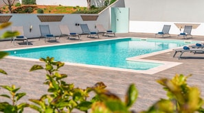 Una piscina amb gandules, una terrassa enrajolada i una paret amb un disseny geomètric.