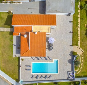 Oversigtsbillede af et hotel med swimmingpool, udendørs siddeområde og en overdækket terrasse.
