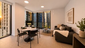 A modern living room with a dining area, a sofa, and a large window with a view of high-rise buildings. - Downtown Miami 1BR with City Views (Miami)