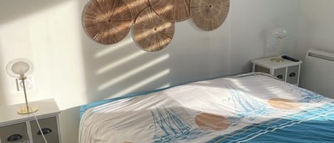 A bedroom with a bed, bedside tables, wall sconces, and a decorative wall hanging.