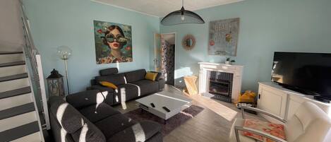 A living room with a sofa, coffee table, TV, fireplace, and artwork.