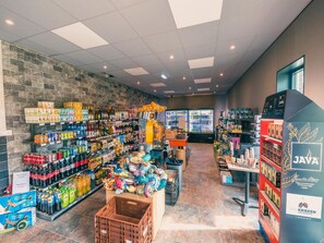 Ein Supermarktinneres mit Regalen voller Getränke, Snacks und einer Kühltheke.