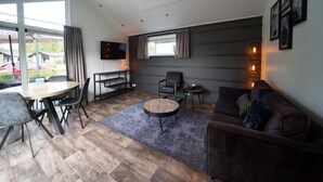 Ein modernes Wohnzimmer mit Essbereich, einem Flachbildfernseher und einer Couch.