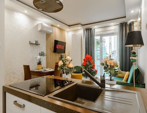 A modern kitchen with a built-in stove, a sink, and a dining area with a table and chairs. - Flat Near Metro, Warsaw (Warsaw)