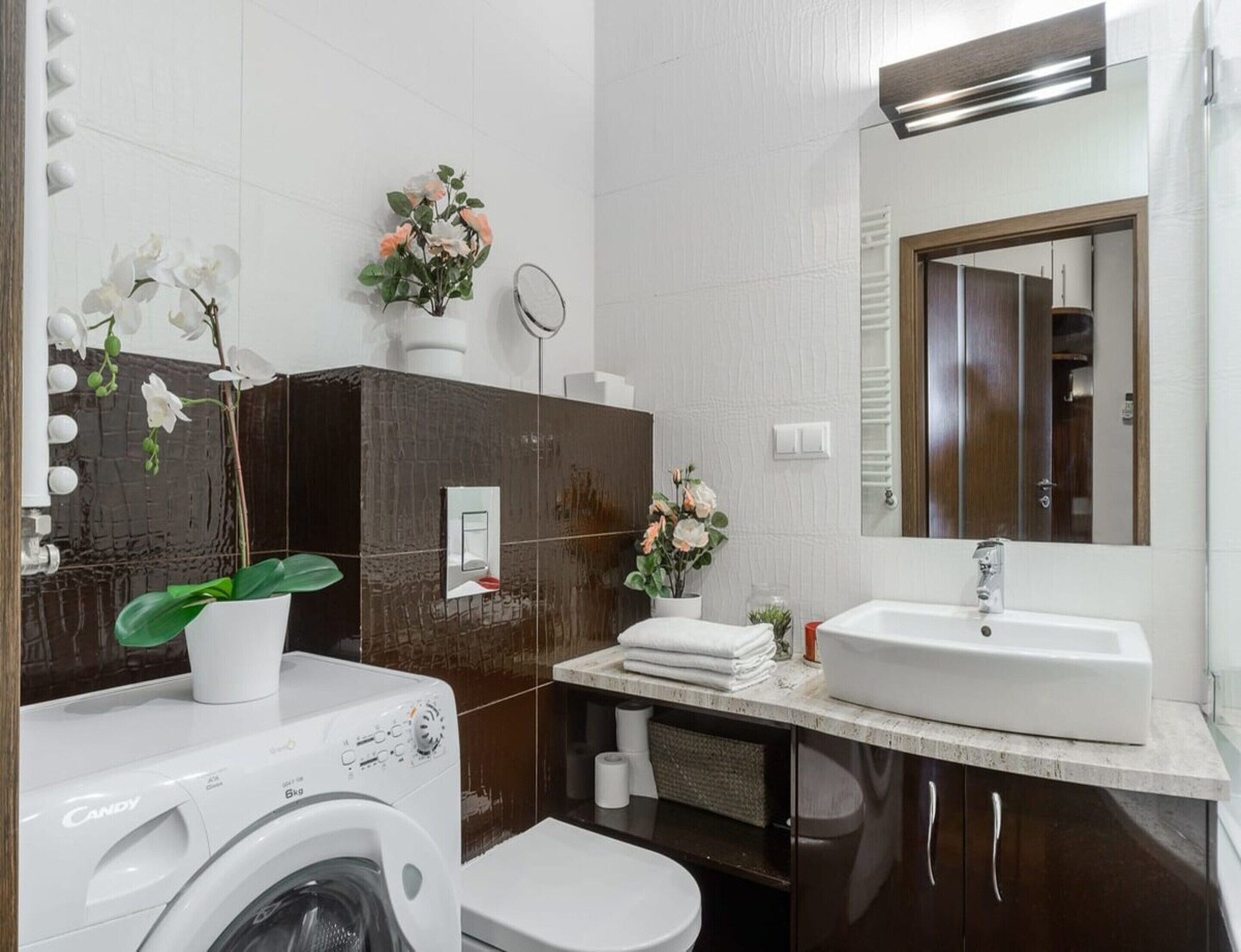 Une salle de bain moderne équipée d’un lave-linge, d’un évier et d’un miroir.