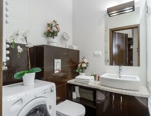 Une salle de bain moderne équipée d’un lave-linge, d’un évier et d’un miroir.