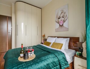 Ein Hotelzimmer mit Bett, Minibar, einem Bild an der Wand und einer Tür.