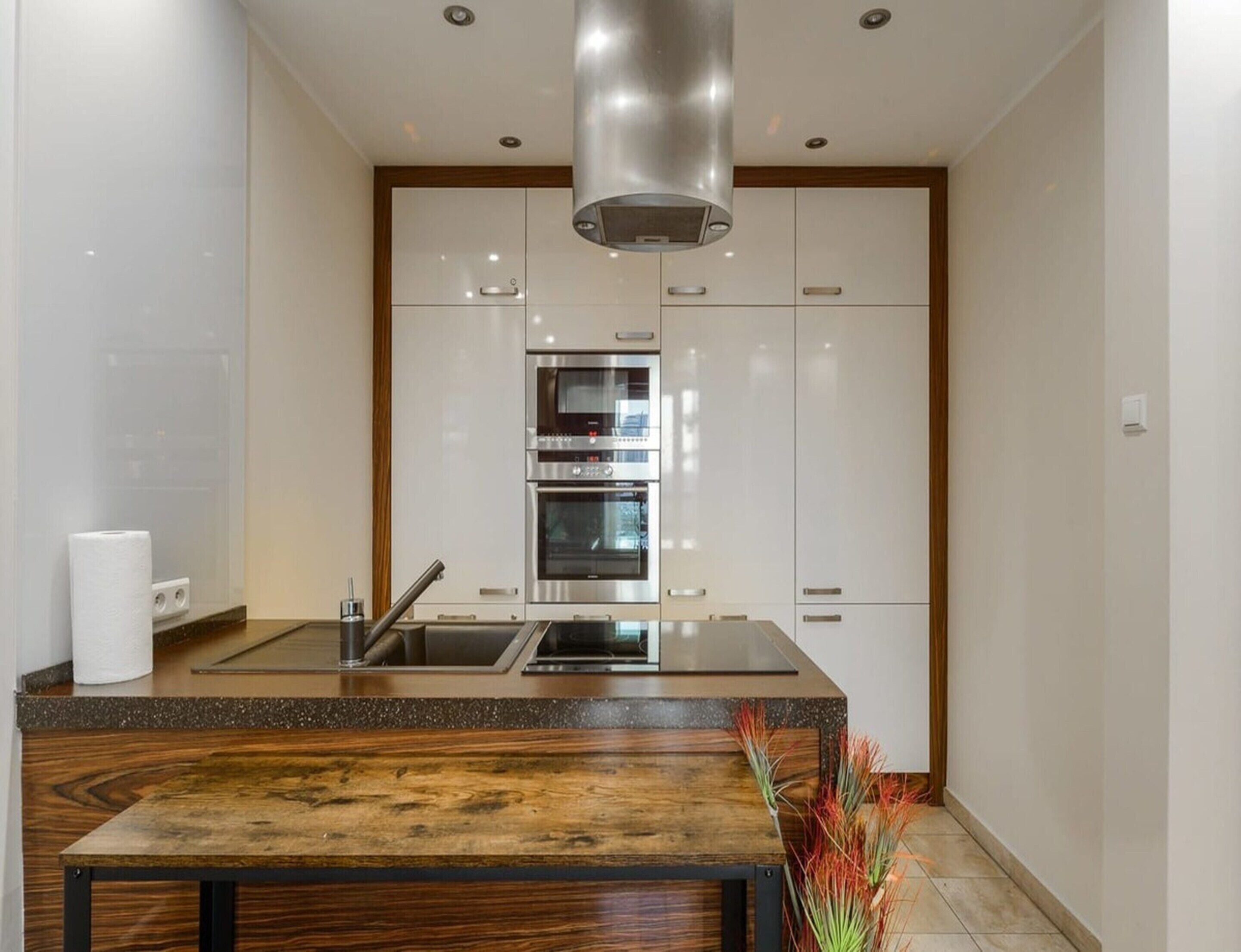 Une cuisine moderne dotée d’un îlot central, d’appareils électroménagers en acier inoxydable et d’une table en bois.