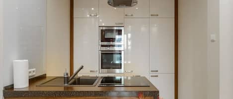 Una cocina moderna con una isla central, electrodomésticos de acero inoxidable y una mesa de madera.