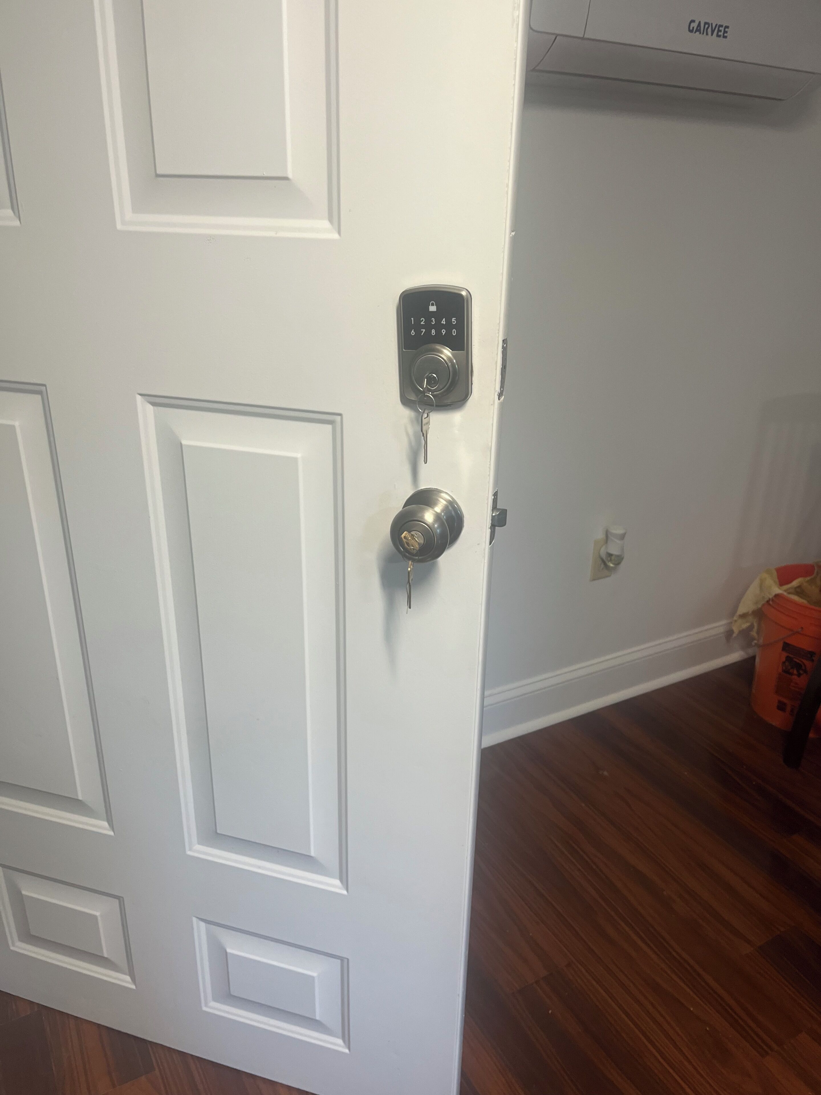 A white door with a keypad lock and a keyhole.