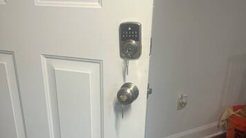 A white door with a keypad lock and a keyhole.