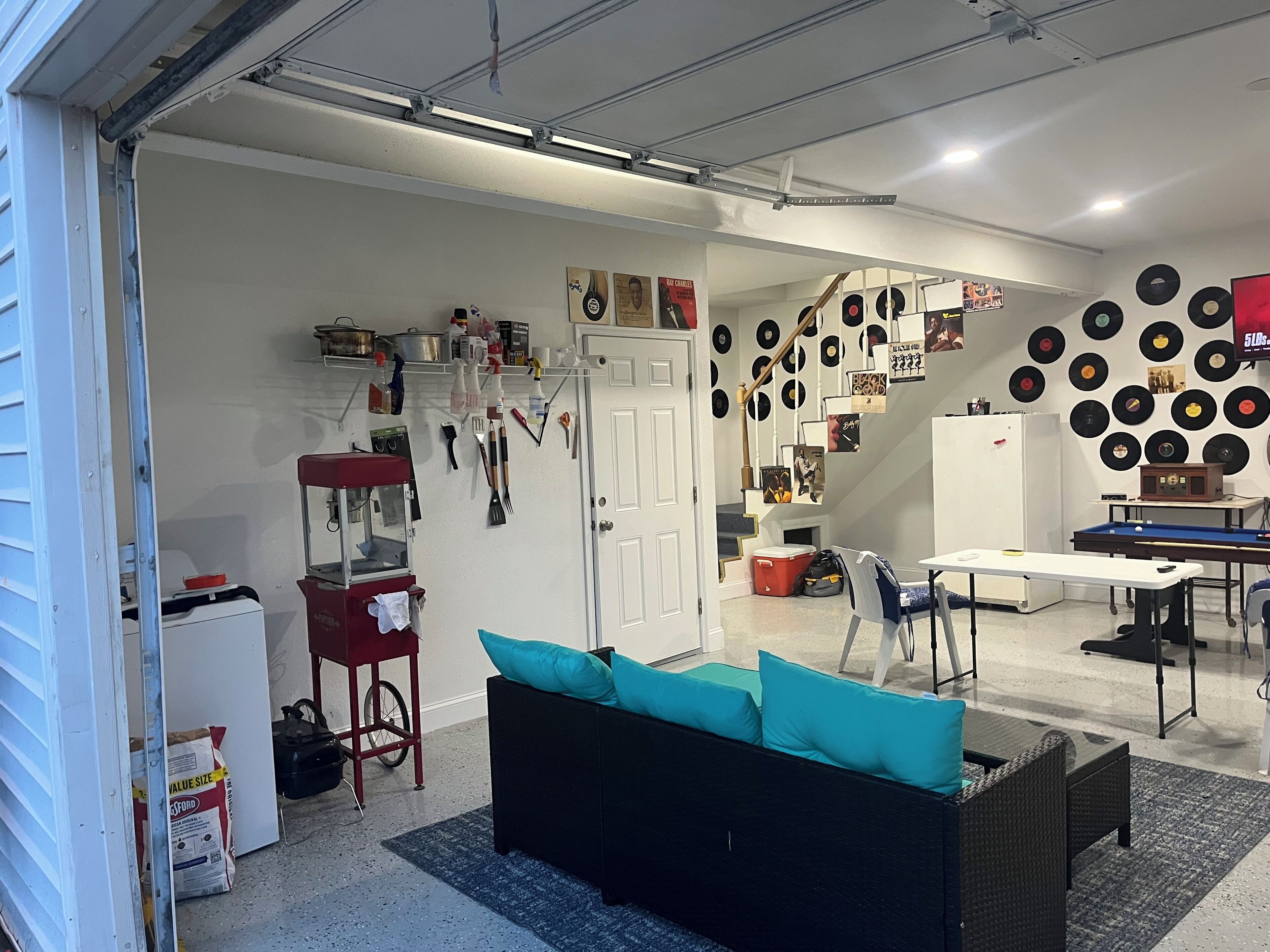 A room with a sofa, a dining table, and a wall decorated with vinyl records.
