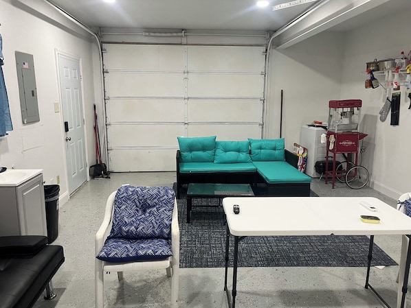 A compact room with a teal sofa, a white table, and a black chair.