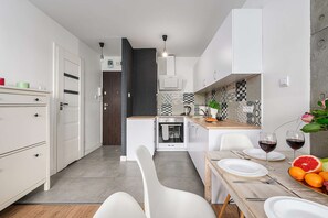 Eine moderne Küche mit weißen Schränken, einem eingebauten Backofen und einem Essbereich mit Tisch für zwei Personen.