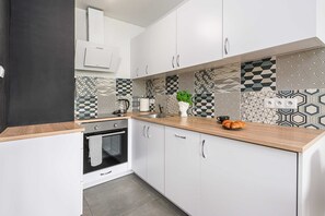 A modern kitchen with white cabinets, a wooden countertop, and patterned backsplash tiles. - Sunlit Home With City Views (Warsaw)
