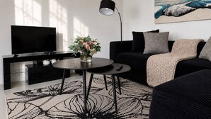 A modern living room with a flat-screen TV, a round coffee table, a sofa, and a painting on the wall.