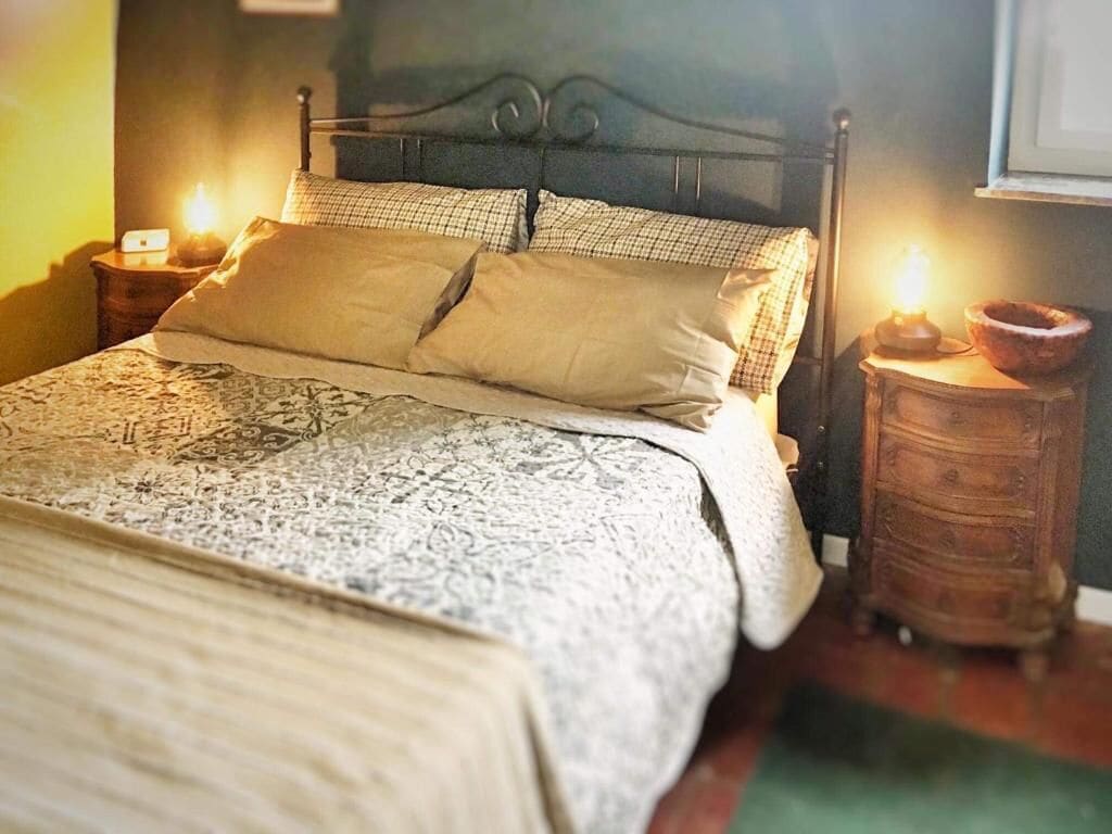 Ein Bett mit einem gemusterten Bettüberwurf, zwei Kissen und zwei Nachttische mit Lampen.