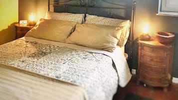 Ein Bett mit einem gemusterten Bettüberwurf, zwei Kissen und zwei Nachttische mit Lampen.
