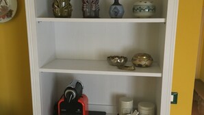 A white shelf unit with decorative items and a coffee maker. - NOI DUE Guesthouse (Fubine)