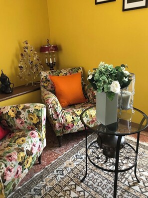 Una sala de estar con sofás de estampado floral, una mesa de centro de vidrio y un tapete estampado.