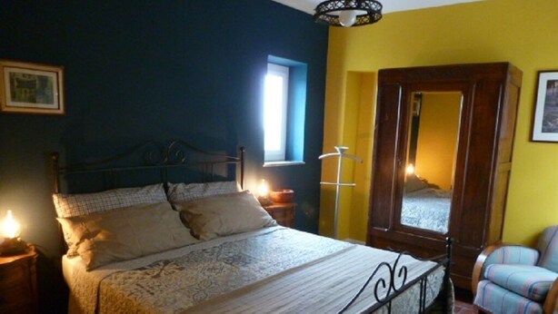 A bedroom with a bed, bedside lamps, a mirror, a chair, and a window. - NOI DUE Guesthouse (Fubine)