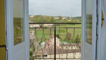 Eine offene Tür mit Blick auf eine Ziegelterrasse und ein Metallgeländer, das auf ein Wohngebiet hinausblickt.