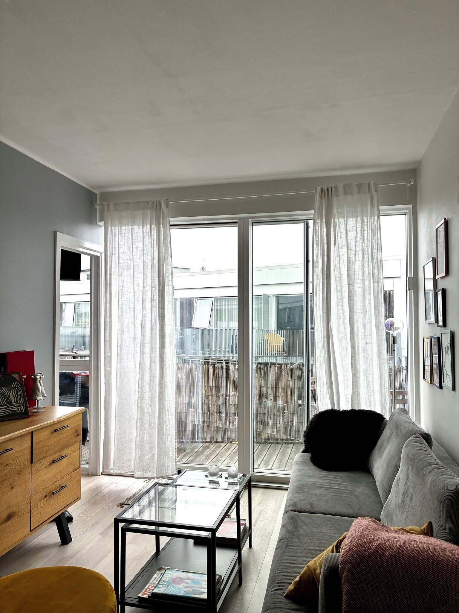 A modern living room with a sofa, a glass coffee table, and a wooden cabinet.