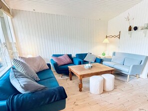 A living room with a blue sofa, a grey sofa, a wooden coffee table, and a light blue sofa. - 5 Star Holiday Home in Glesborg (Glesborg)