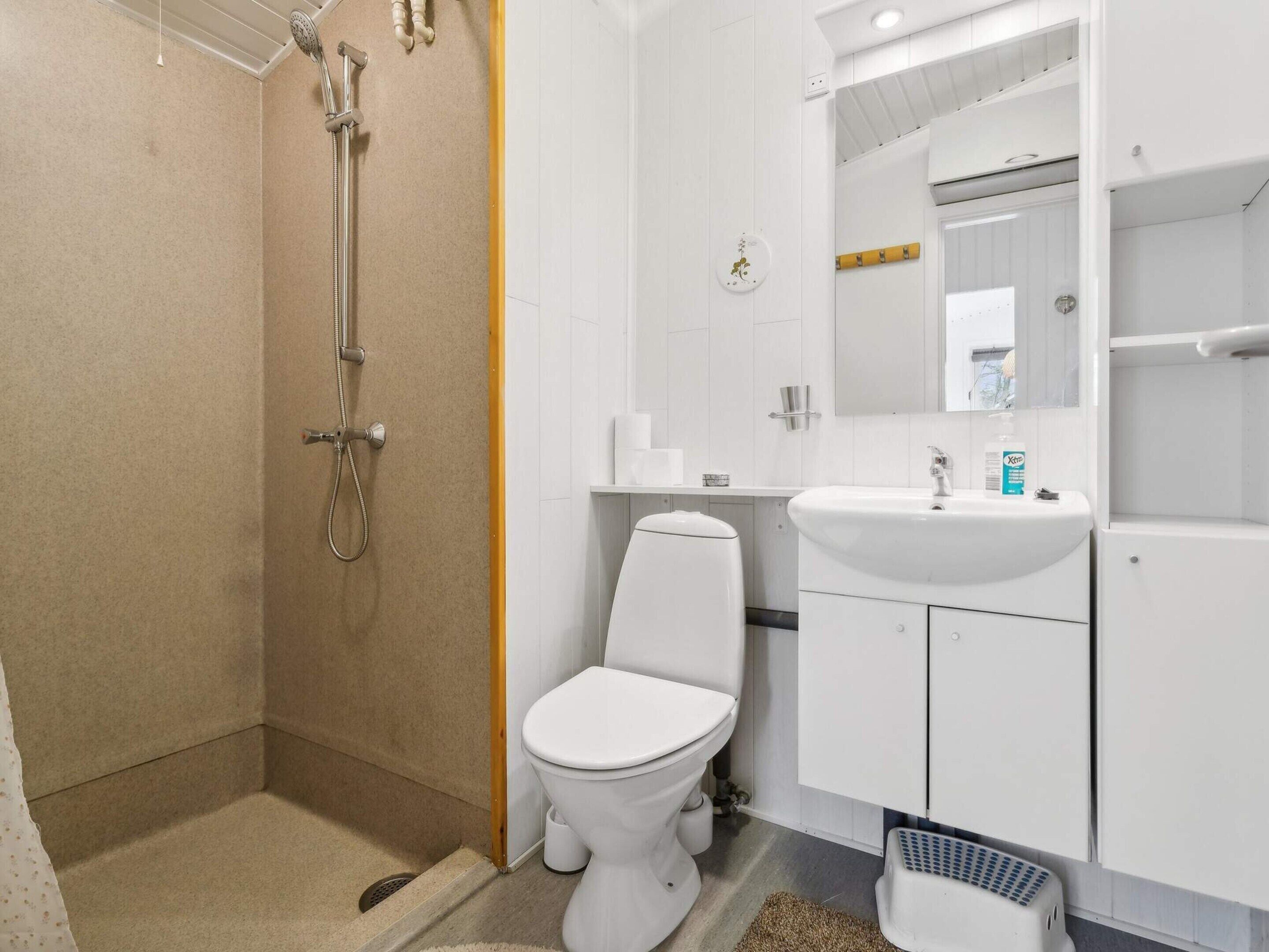 A bathroom with a shower, toilet, sink, and a mirror.