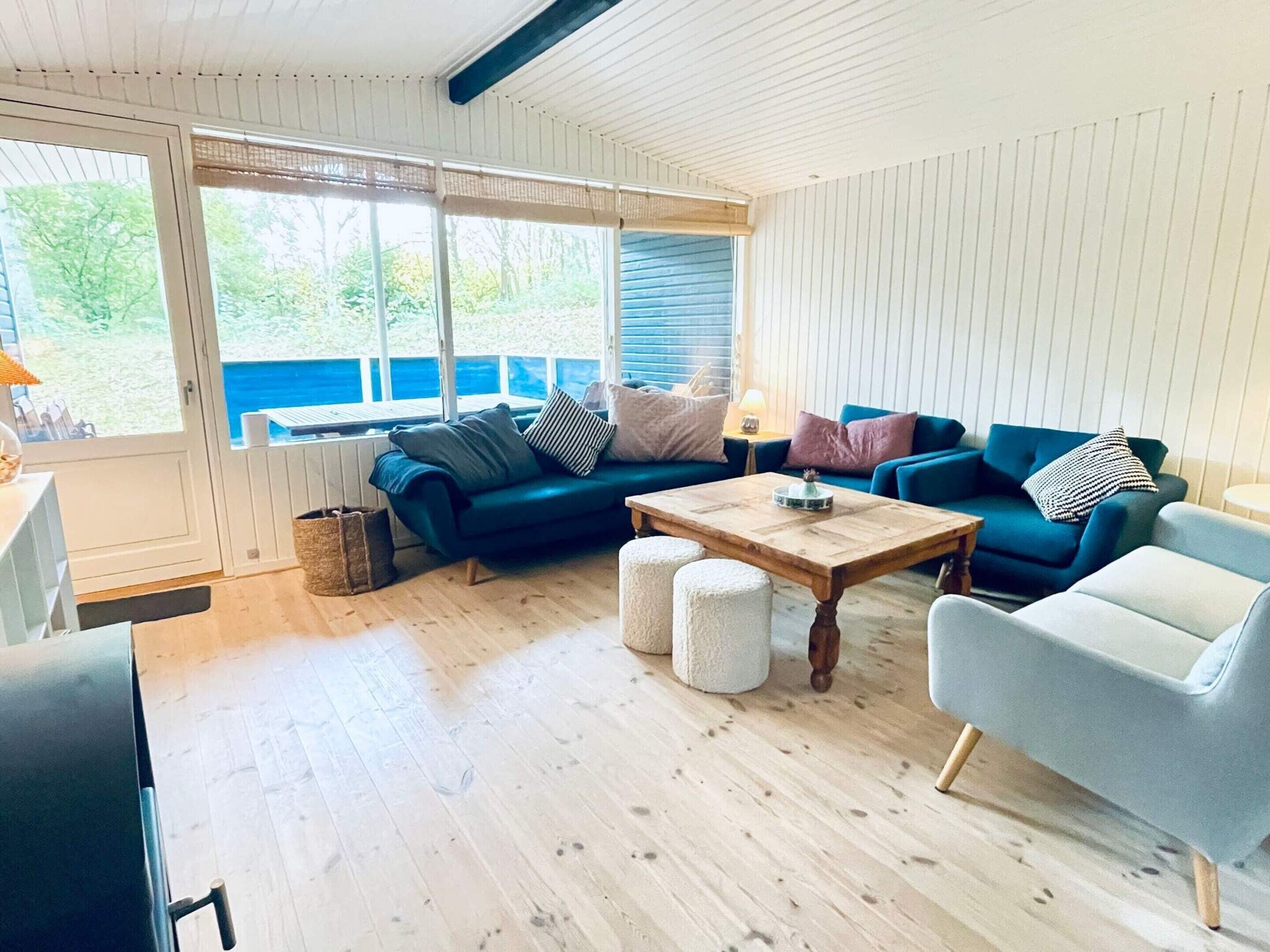 Un salon chaleureux avec un canapé bleu, une table basse en bois et un fauteuil gris.