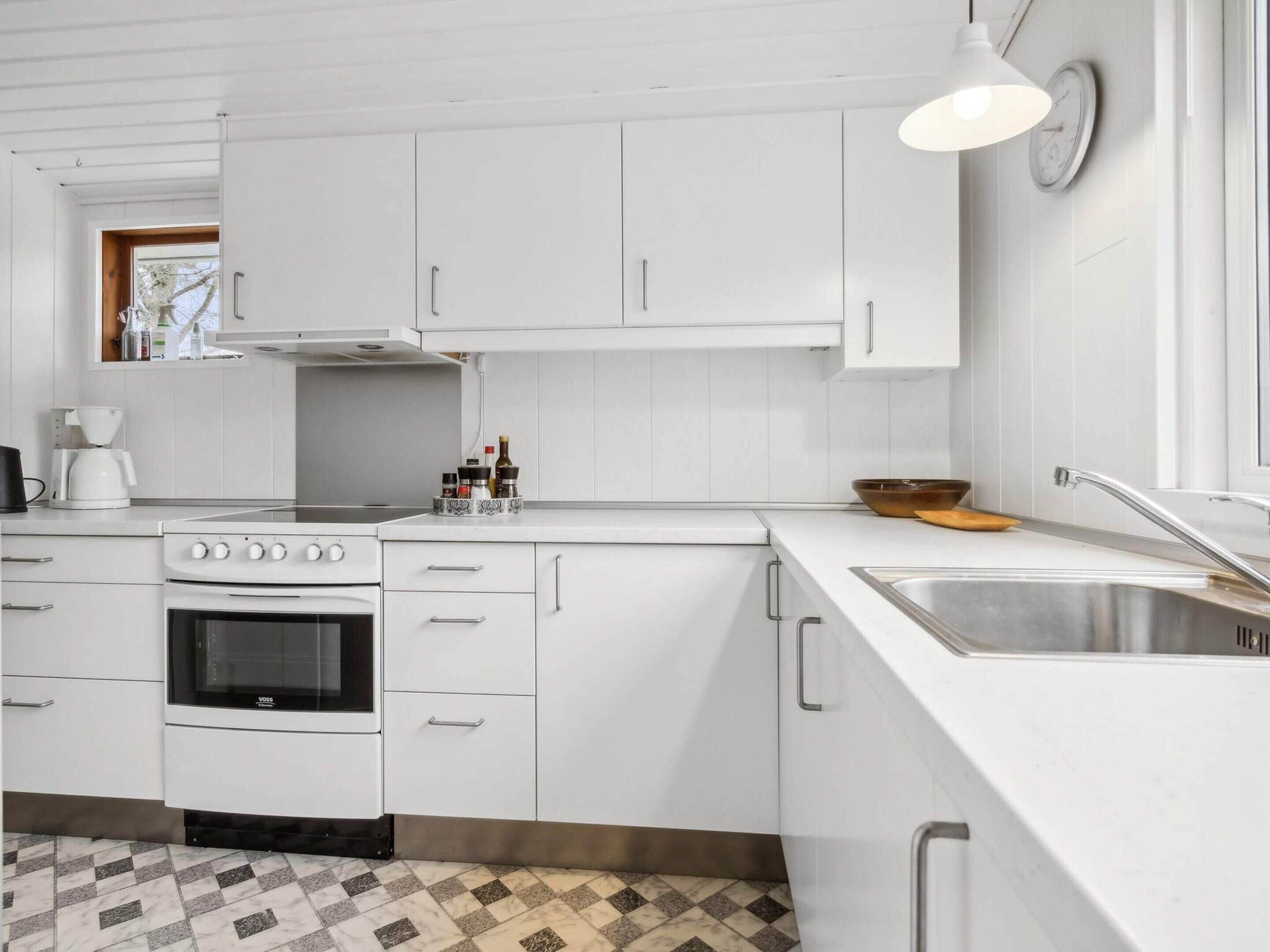 A modern kitchen with white cabinetry, a built-in oven, a coffee maker, and a sink.