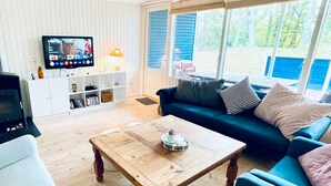 A living room with a wooden coffee table, a blue sofa, and a television on the wall. - 5 Star Holiday Home in Glesborg (Glesborg)