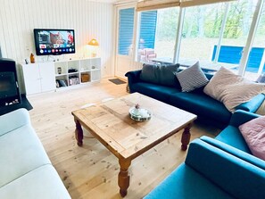 A living room with a wooden coffee table, a blue sofa, and a television on the wall. - 5 Star Holiday Home in Glesborg (Glesborg)