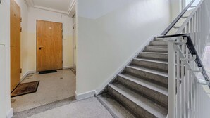 A hallway with a wooden door, a carpeted floor, and a staircase with a metal railing. - Warsaw Stay Near Cinema (Warsaw)