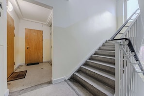 A hallway with a wooden door, a carpeted floor, and a staircase with a metal railing. - Warsaw Stay Near Cinema (Warsaw)