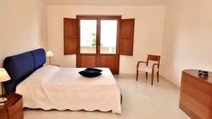 A bedroom with a bed, a chair, a dresser, and a window with open shutters. - Villa in Valderice With Pool and Garden (Valderice)
